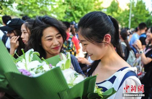 資料圖：山東濟南眾多考生手捧鮮花在家長的簇?fù)硐職g快告別高考。中新社記者 張勇 攝