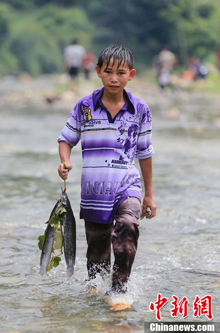 圖為7月9日，一名男孩在鬧魚節(jié)活動中抓到了兩條魚。譚凱興 攝