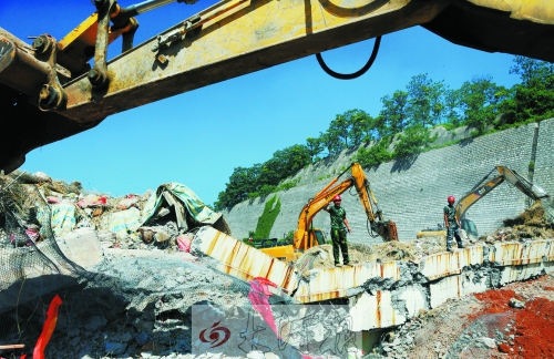 為確保道路盡早通車，工人師傅冒著烈日，指揮施工機械清理爆破現(xiàn)場